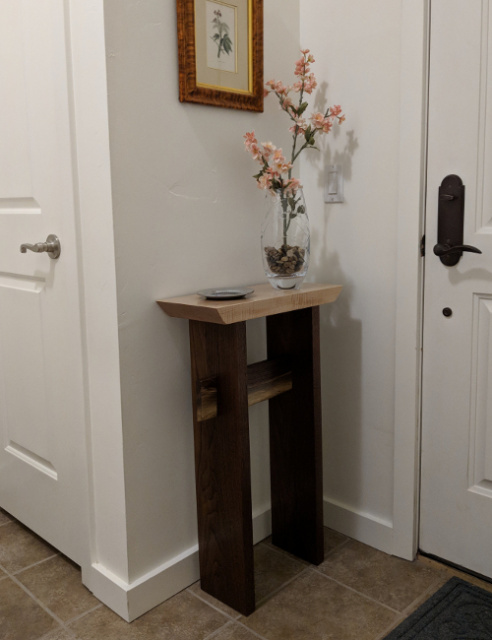 Our statement accent table looks lovely in a small entryway space- created in tiger maple and walnut with a live edge table stretcher