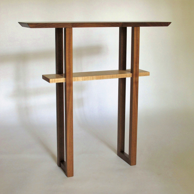 A narrow entry table with shelf in walnut and tiger maple wood